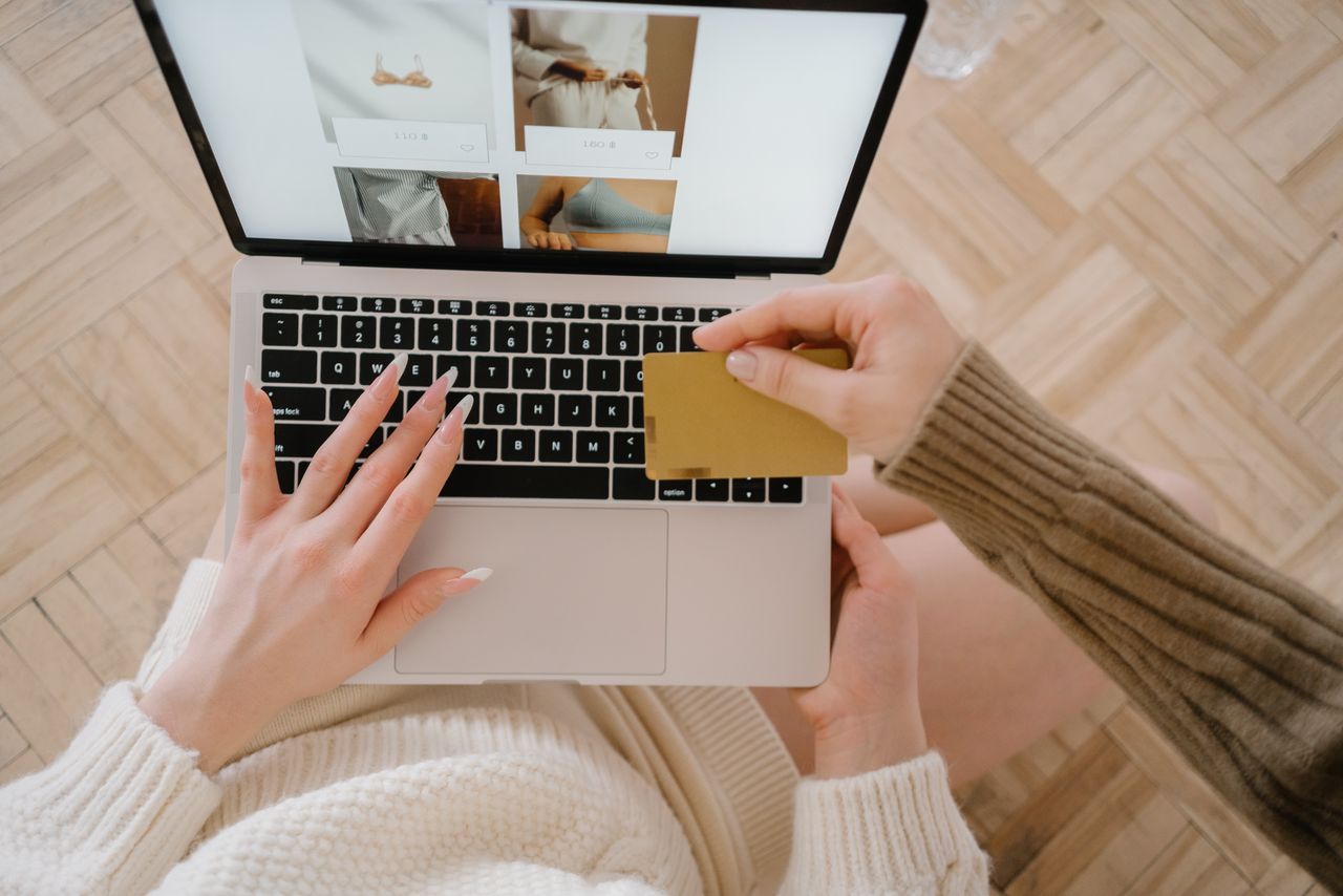 Osoba koja kupuje online koristeći prijenosno računalo i kreditnu karticu, naglašavajući praktičnost e-trgovine.